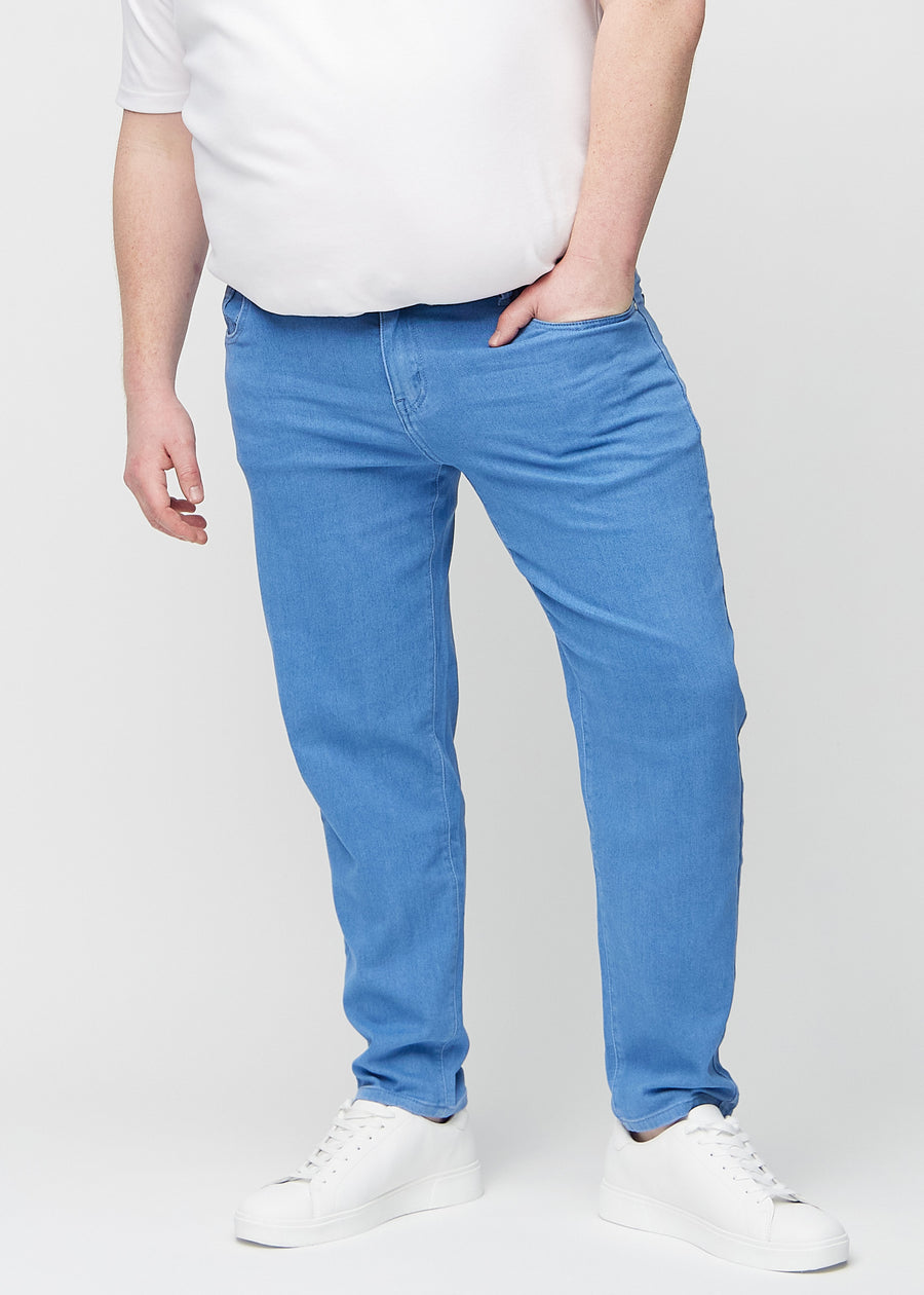 Blå regular jeans, modellnamn Geraniums, som går rakt ner längs benet på en plus-size-modell, sett framifrån.