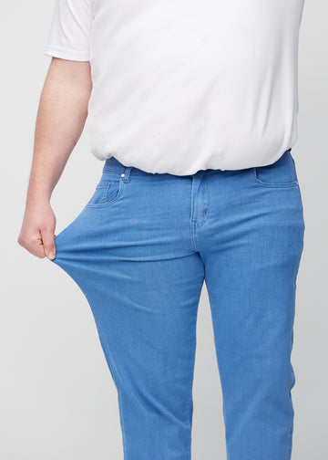 Plus-size-modellen drar ut jeansen vid låret för att visa stretch.