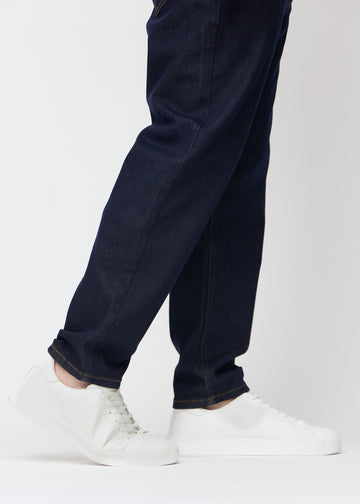 Djup mörkblå denim jeans för män i färgen Midnights med regular passform sedd på nära håll vid anklarna på plus-size-modell för att visa det raka avslutet.