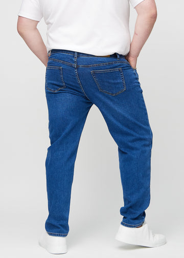 Mörkblå denim regular jeans sedd bakifrån på en plus-size-modell, så att man kan se hela produkten.