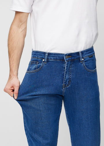 Modellen sträcker jeansen vid låret för att visa stretch.