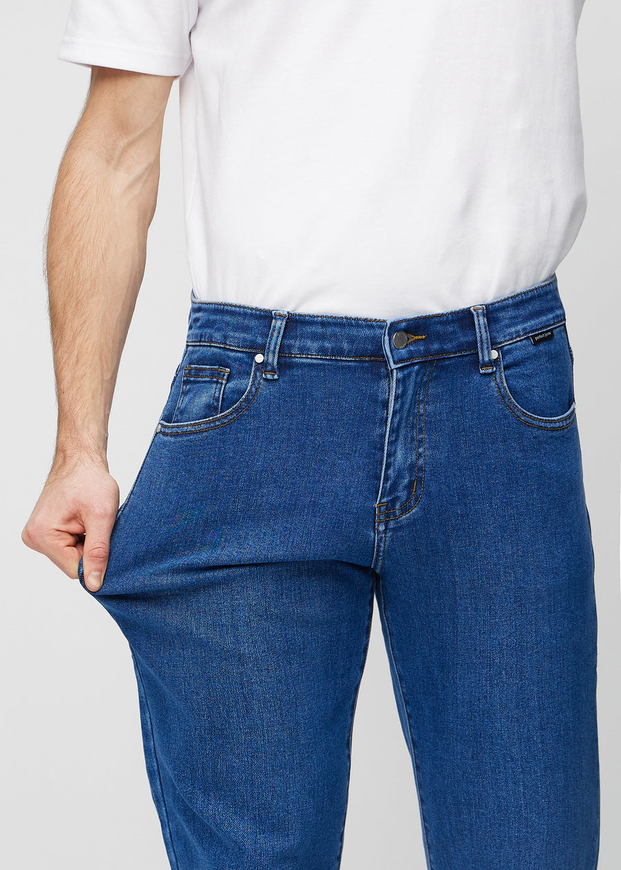 Modellen sträcker jeansen vid låret för att visa stretch.