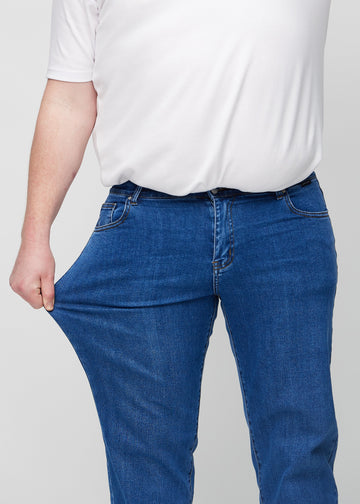 Plus-size-modellen sträcker jeansen vid låret för att visa stretch.