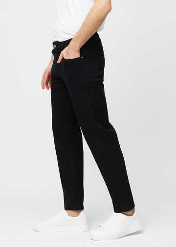 Svarta regular jeans sett från sidan på modell.