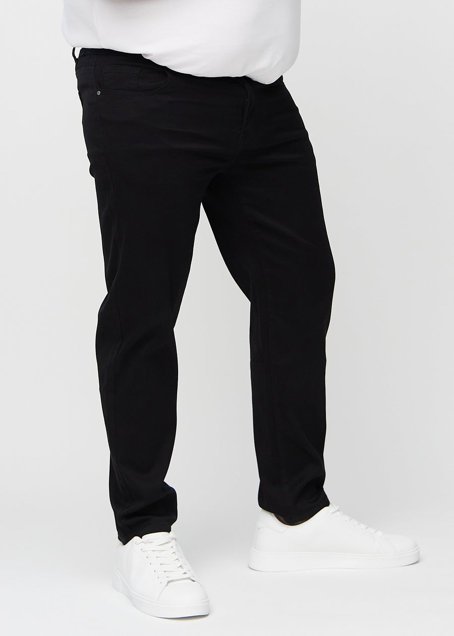 Svarta regular jeans, modellnamn Ravens, som går rakt ner längs benet på en plus-size-modell, sett framifrån.