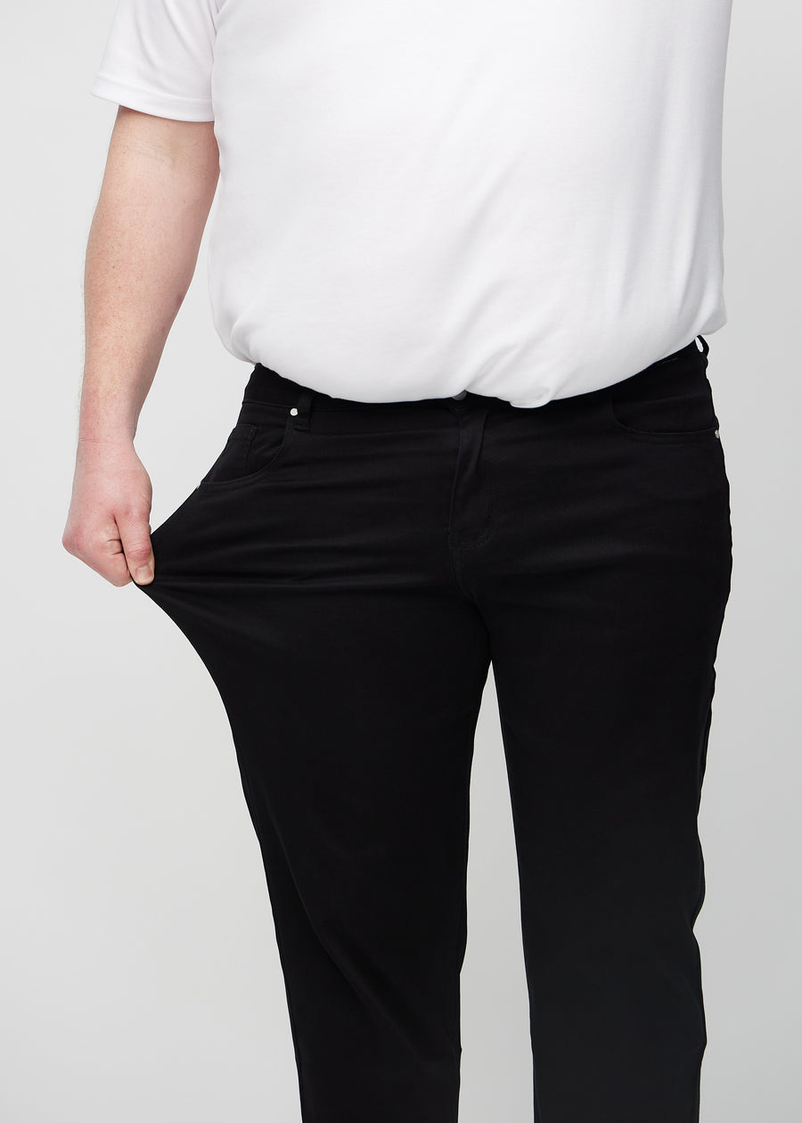 Plus-size-modellen sträcker ut jeansen vid låret för att visa stretch.