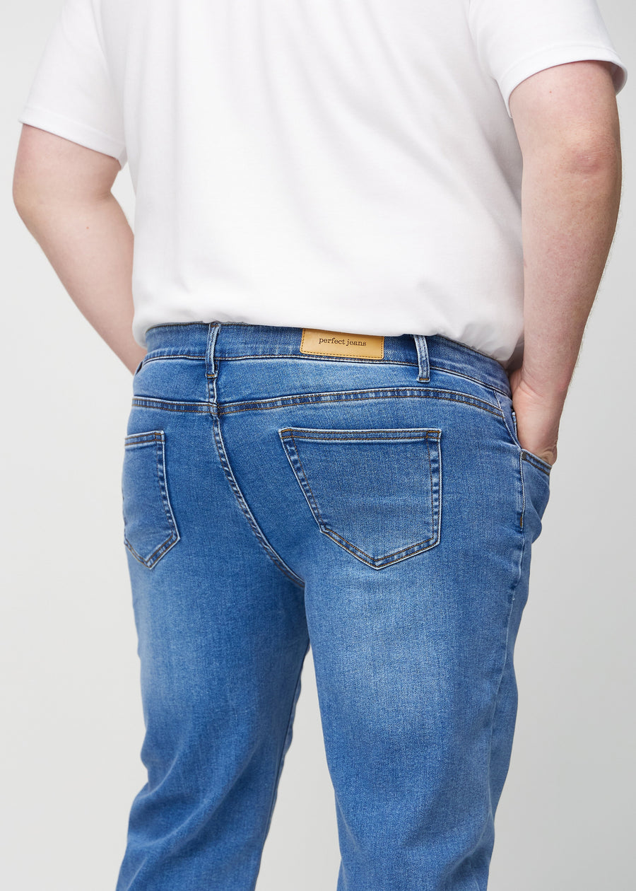 Närbild bakifrån av denimjeans i regular fit på en plus size-modell som visar detaljerna.