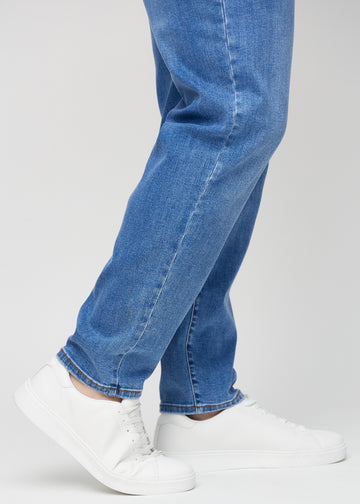 Närbild av en plus size-modells anklar som visar hur löst jeansen sitter.