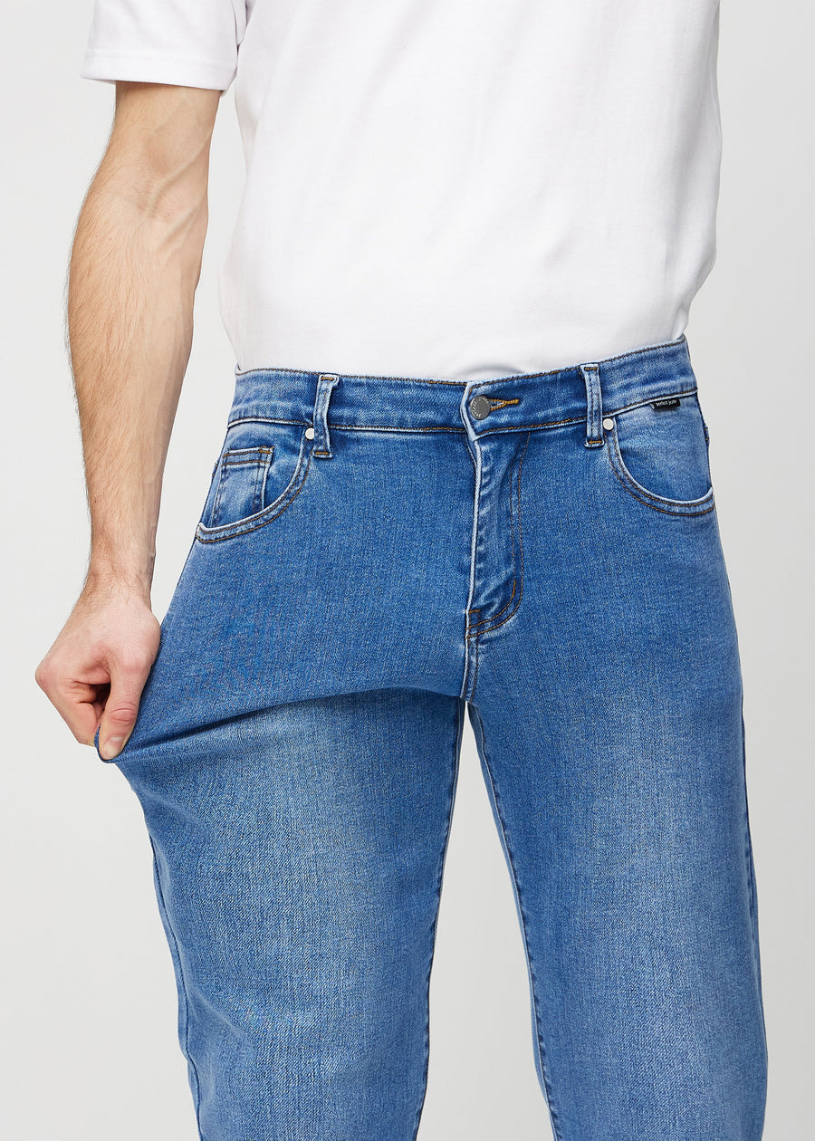 Modellen drar ut jeansens tyg vid låret för att visa stretchen.
