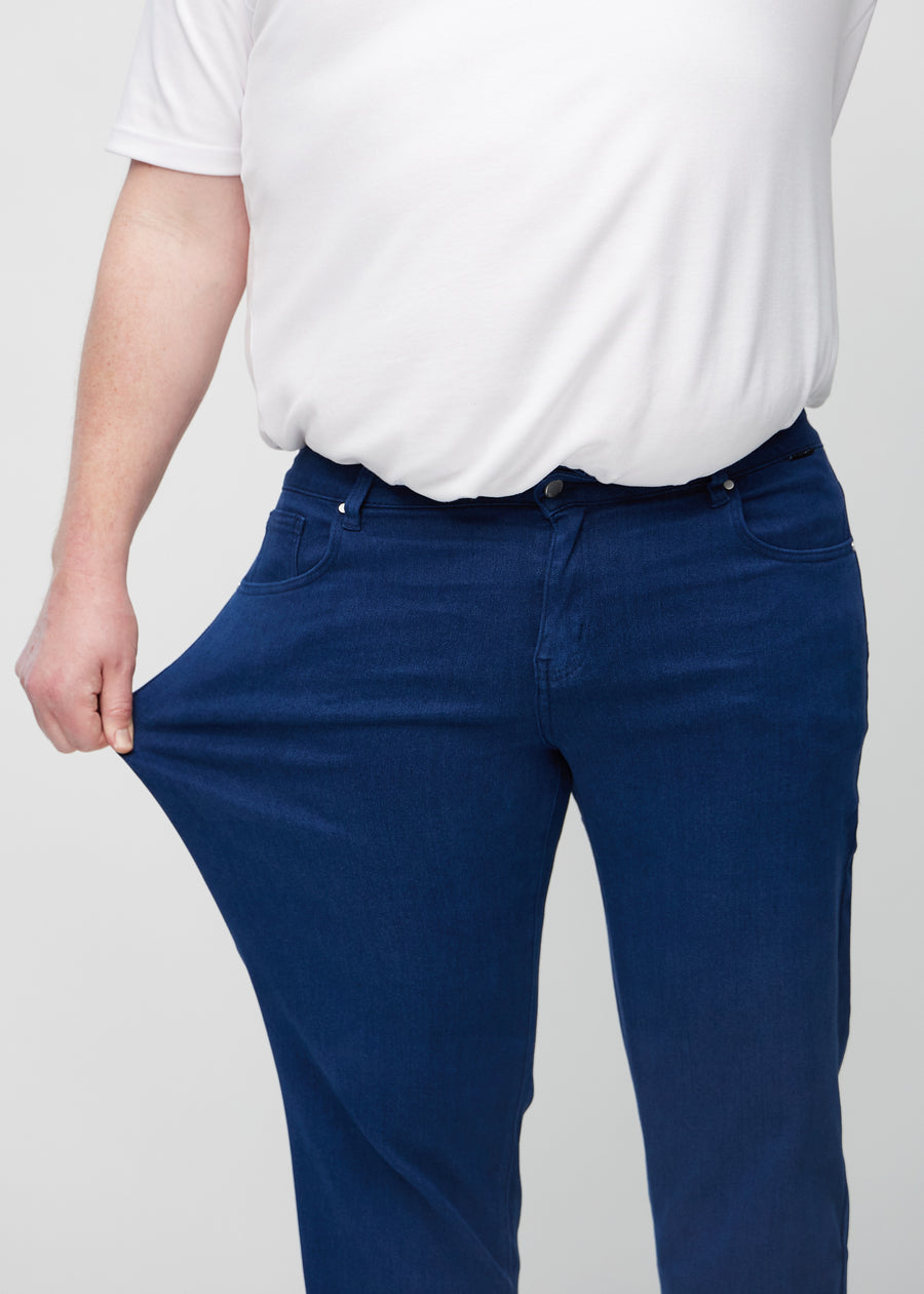 Plus-size-modellen sträcker jeansen vid låret för att visa stretch.