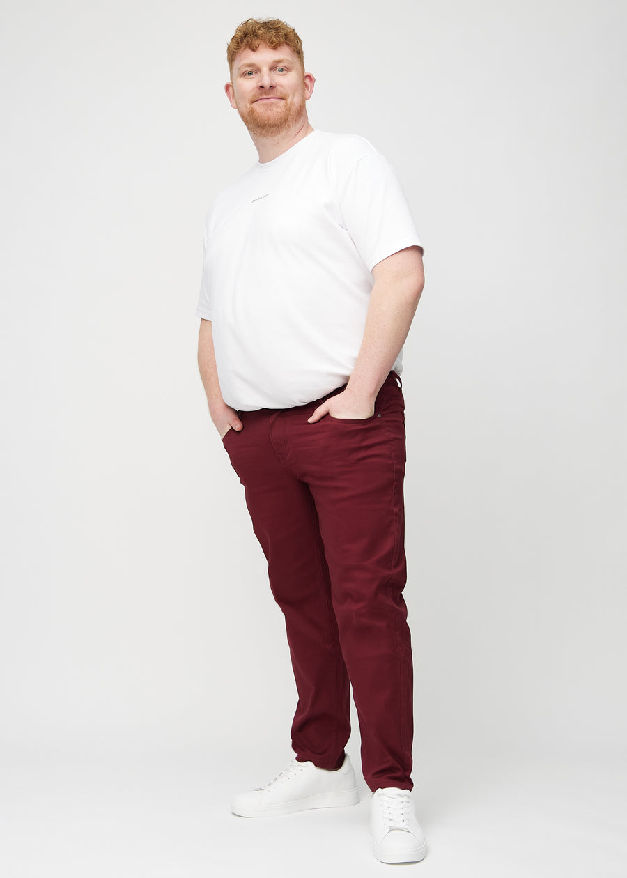 Helbild på en plus-size-modell i mörkröda regular jeans.