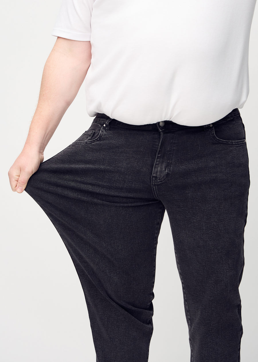 Plus-size-modellen drar ut jeansen vid låret för att visa stretch.