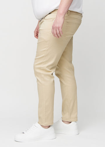 Beige jeans i slim fit sedda från sidan på en plus size-modell.