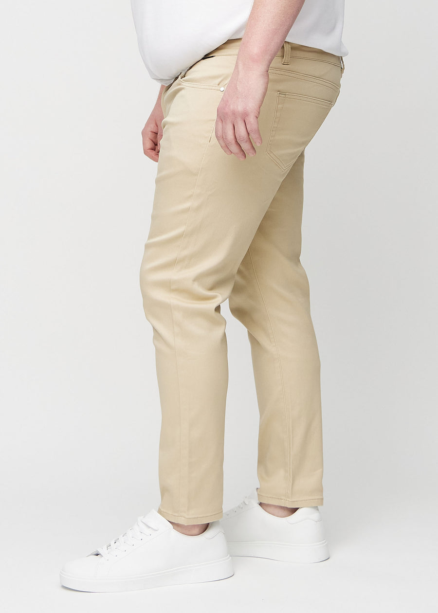 Beige jeans i slim fit sedda från sidan på en plus size-modell.