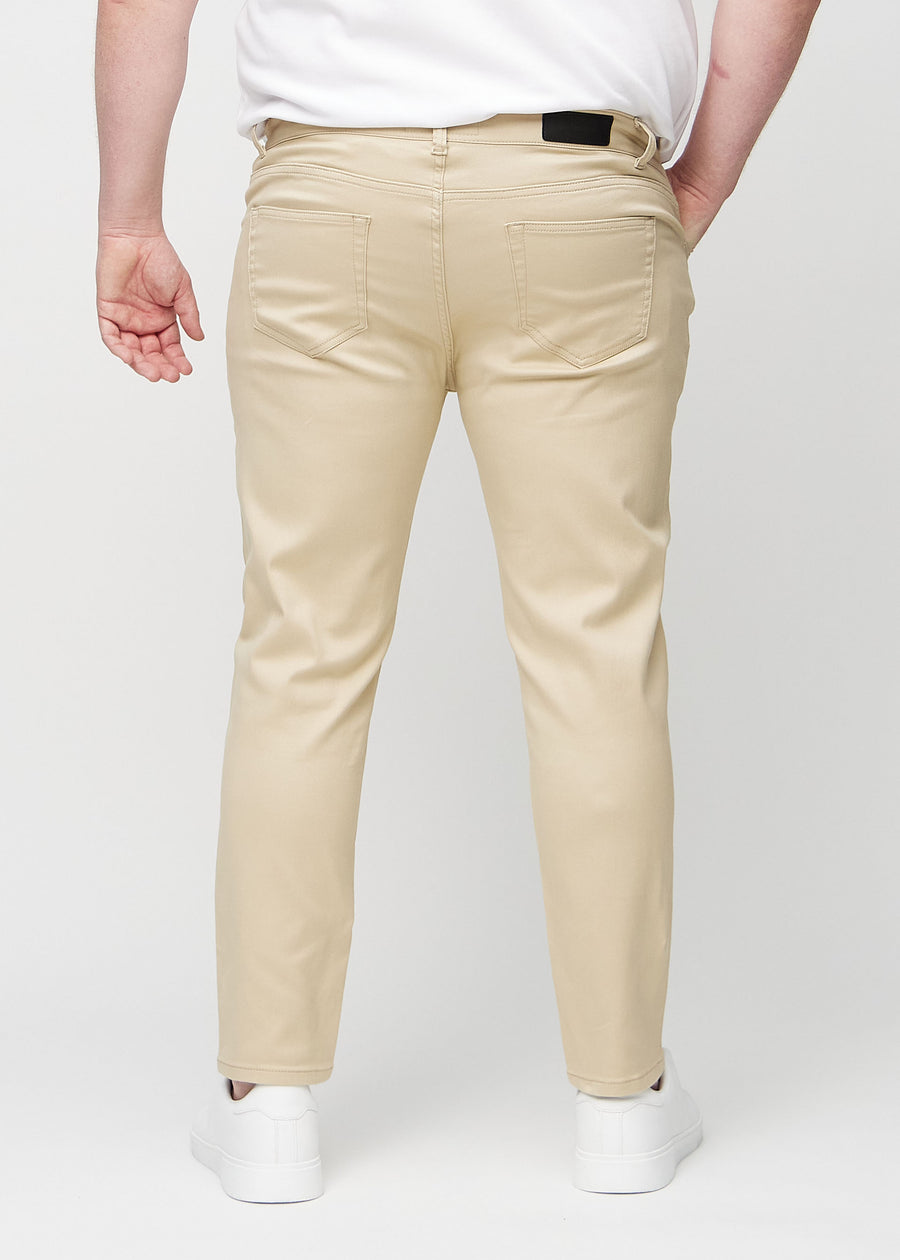 Beige jeans i slim fit sedda bakifrån på en plus size-modell för att visa hela produkten.