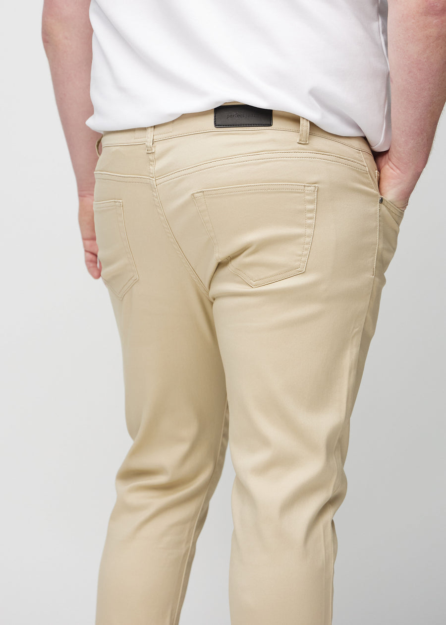 Närbild bakifrån av beige jeans i slim fit på en plus size-modell som visar detaljer.