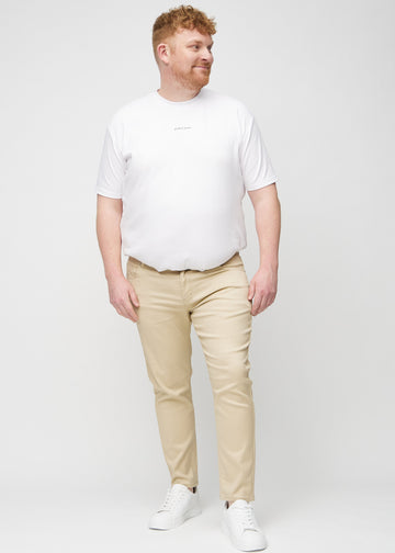 Helbild av en plus size-modell i beige jeans i slim fit.