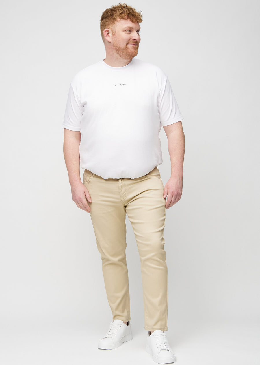 Helbild av en plus size-modell i beige jeans i slim fit.