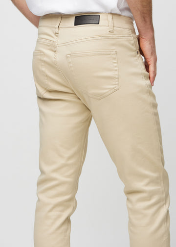 Närbild bakifrån av beige jeans i slim fit som visar detaljer.