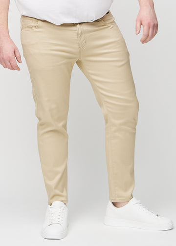 Beige jeans i slim fit, modellnamn Gazelles, som sitter tätt längs benen på en plus size-modell, sedda framifrån.