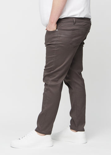 Gråbruna jeans i slim fit sedda från sidan på en plus size-modell.