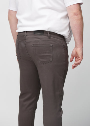Närbild bakifrån av gråbruna jeans i slim fit på en plus size-modell som visar detaljer.