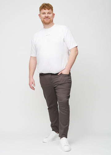 Helbild av en plus size-modell i gråbruna jeans i slim fit.