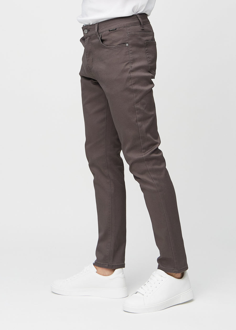 Gråbruna jeans i slim fit sedda från sidan på en modell.