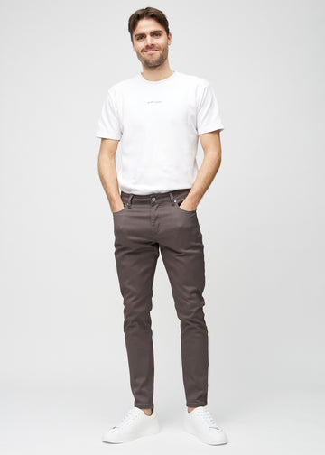 Helbild av en modell i gråbruna jeans i slim fit.