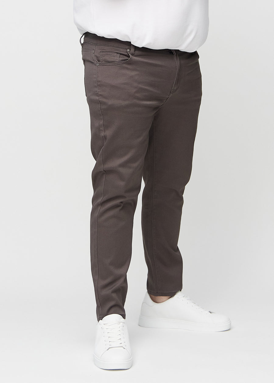 Gråbruna jeans i slim fit, modellnamn Thunders, som sitter tätt längs benen på en plus size-modell, sedda framifrån.
