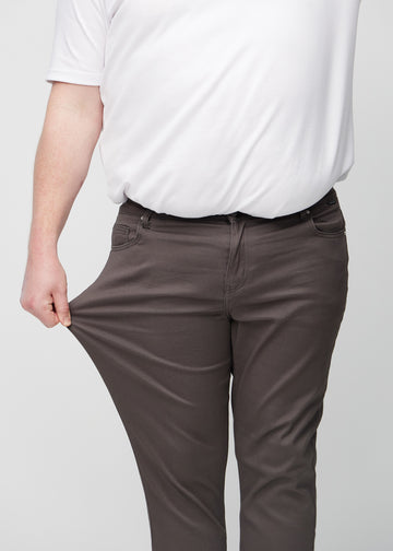Plus size-modell drar i jeansen vid låret för att visa materialets stretch.