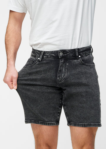 Modell sträcker mörkgrå denimshorts för herr i färgen Shadows vid låret för att visa materialets stretch.