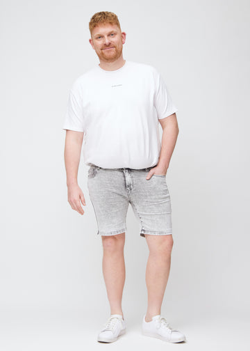 Fuldt billede af en plus-size model i lysegrå denim middle-slim shorts.