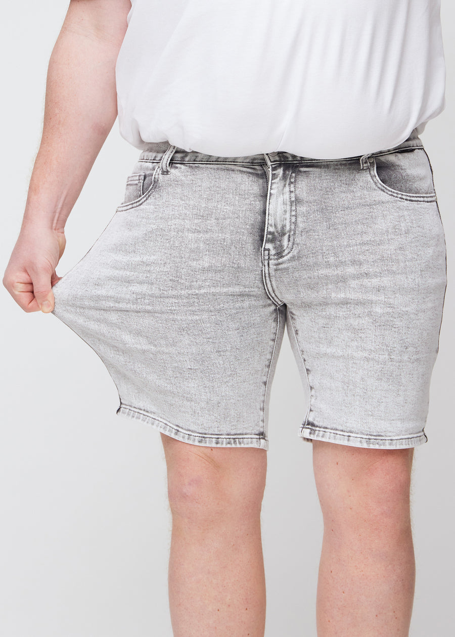 Plus-size model strækker shortsene ved låret for at vise stretch.