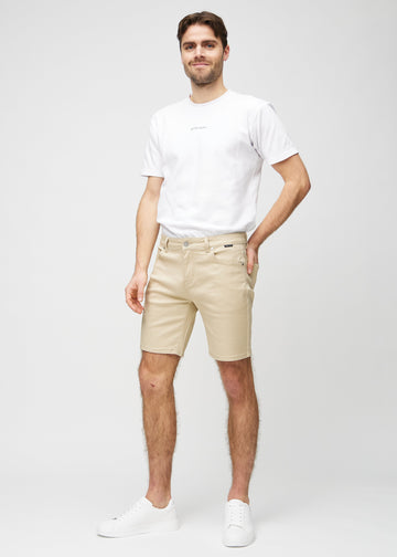 Fuldt billede af model i beige middle-slim shorts.