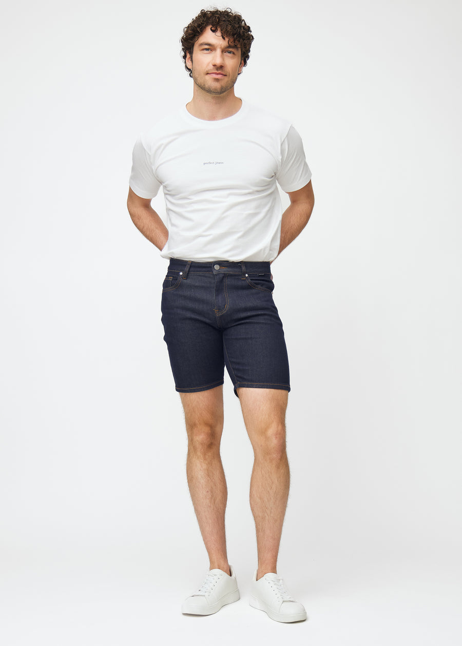 Helbild av modell i mörkblå denimshorts för herr i färgen Midnights med slim passform.