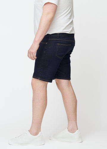 Mörkblå denimshorts för herr i färgen Midnights med slim passform sett från sidan på plus-size modell.