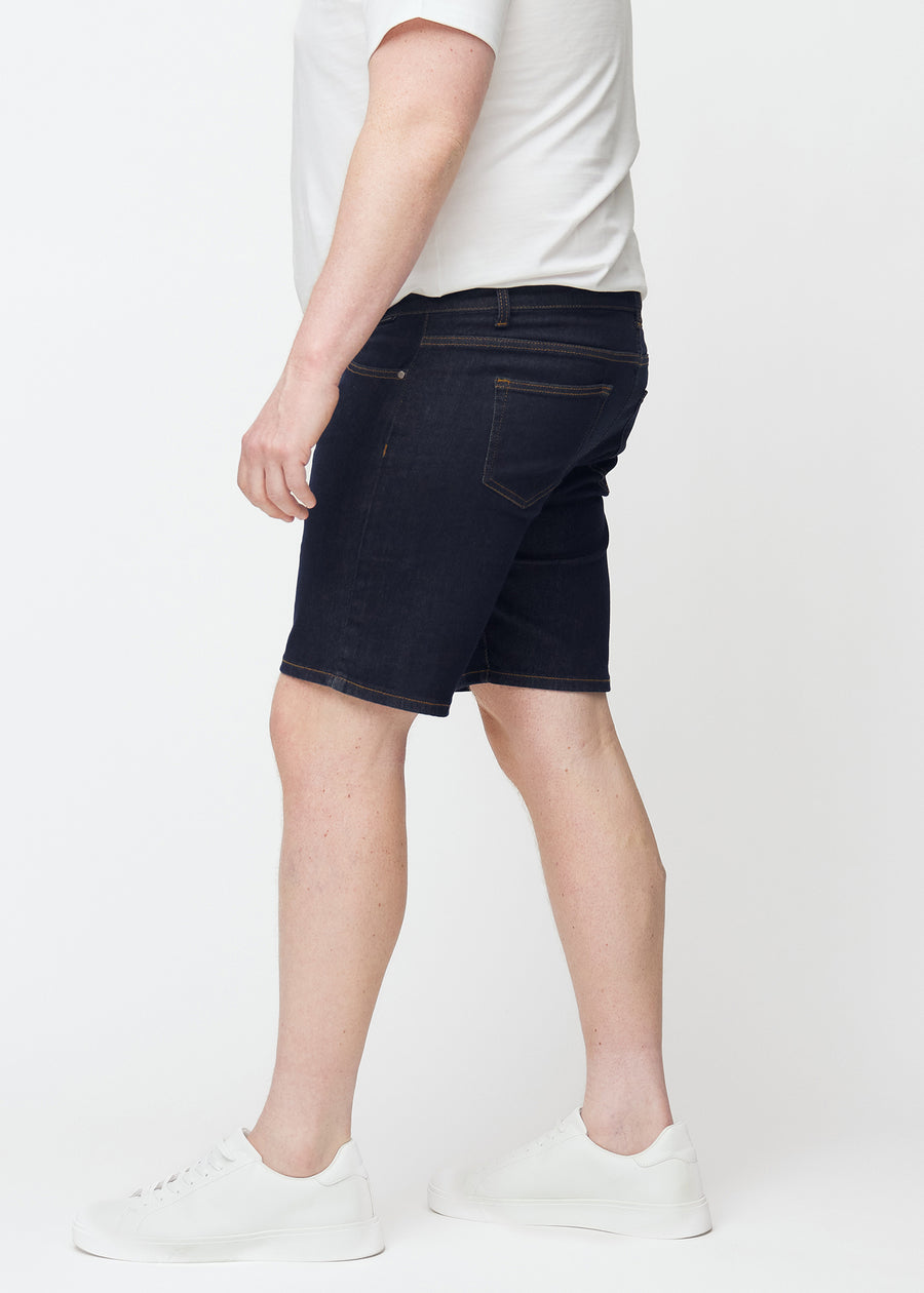 Mörkblå denimshorts för herr i färgen Midnights med slim passform sett från sidan på plus-size modell.