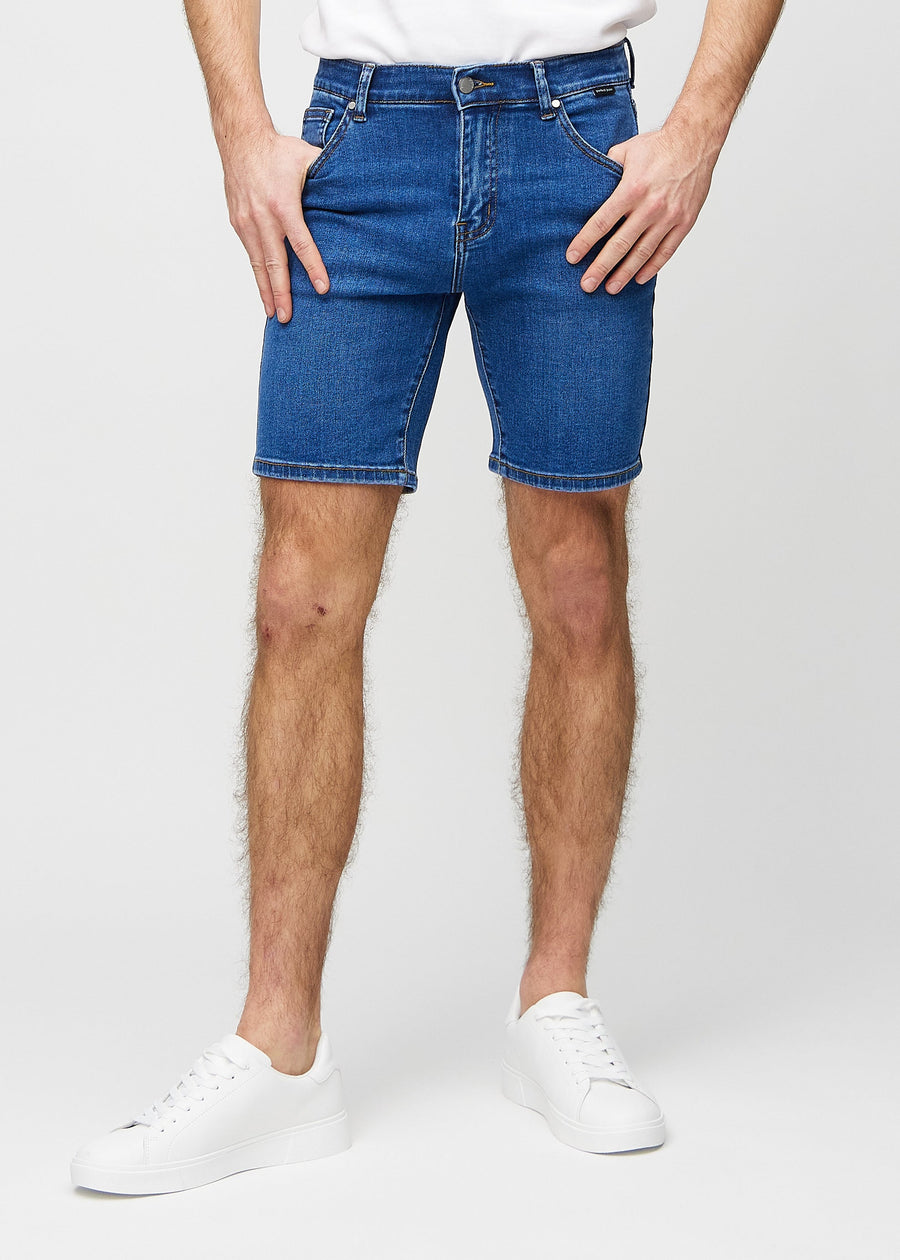 Mörka denim middle-slim shorts, som sitter rakt längs låret och slutar precis ovanför knät, sedda framifrån.