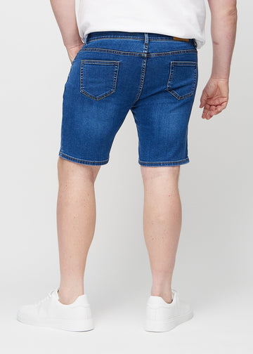 Mörka denim middle-slim shorts sedda bakifrån på en plus size-modell, så att man kan se hela produkten.