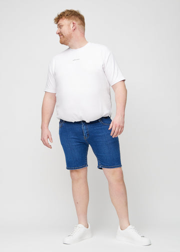 Helbild av en plus size-modell i mörka denim middle-slim shorts.