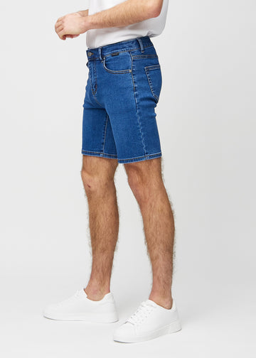 Mörka denim middle-slim shorts sedda från sidan på modell.
