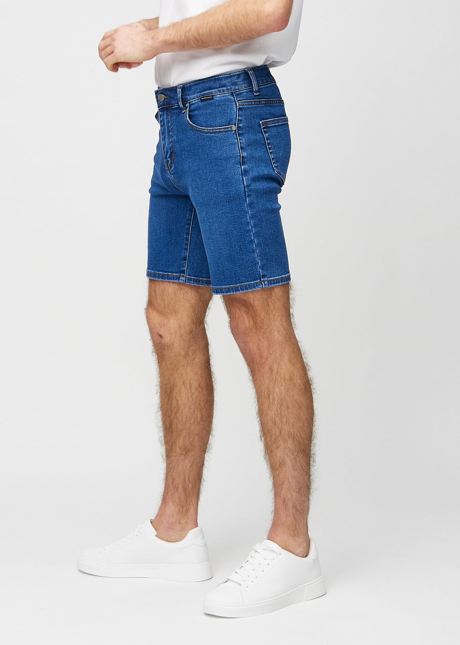 Mörka denim middle-slim shorts sedda från sidan på modell.