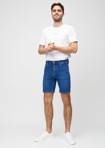Helbild av modell i mörka denim middle-slim shorts.