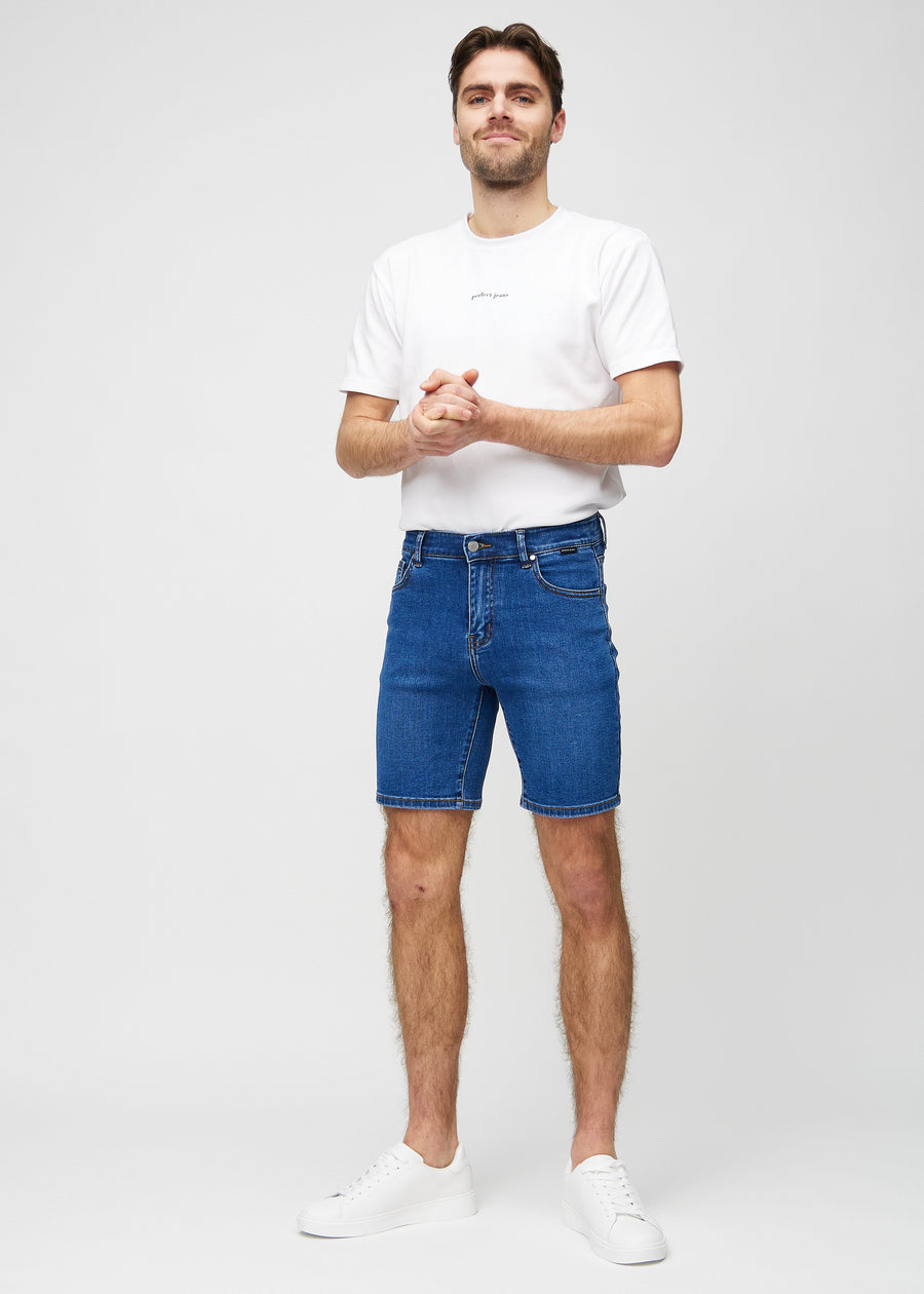 Helbild av modell i mörka denim middle-slim shorts.