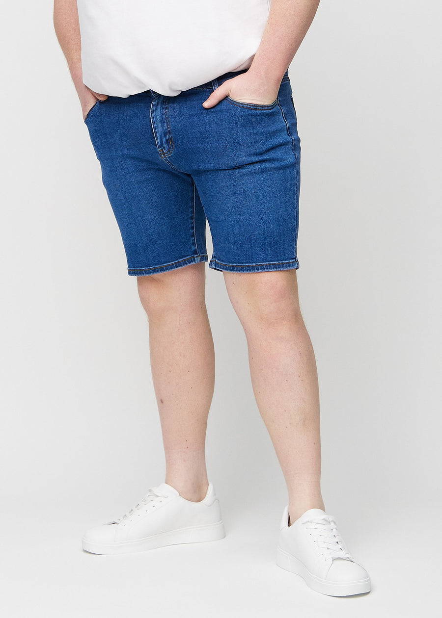 Mörka denim middle-slim shorts, som sitter rakt längs låret och slutar precis ovanför knät på en plus size-modell, sedda framifrån.