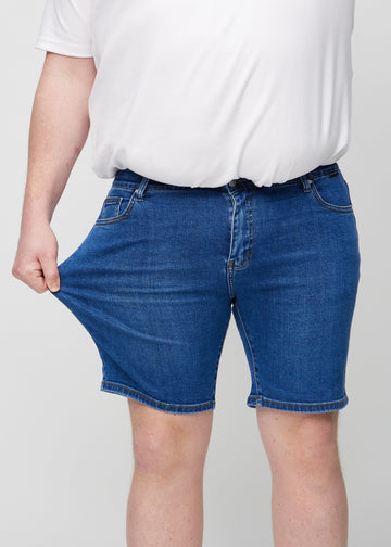 Plus size-modellen sträcker shortsens lårparti för att visa stretch.