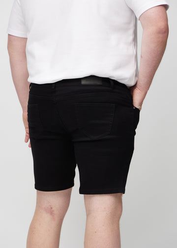 Sorte middle-slim shorts set bagfra tæt på en plus-size model for at vise detaljer.