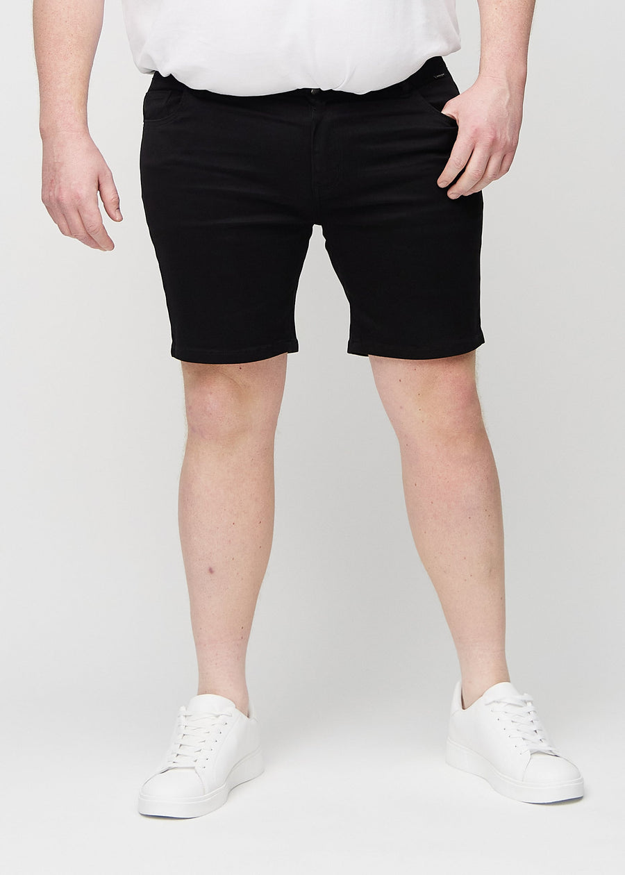 Sorte middle-slim shorts, som sidder lige langs låret og slutter lige over knæet på en plus-size model, set forfra.