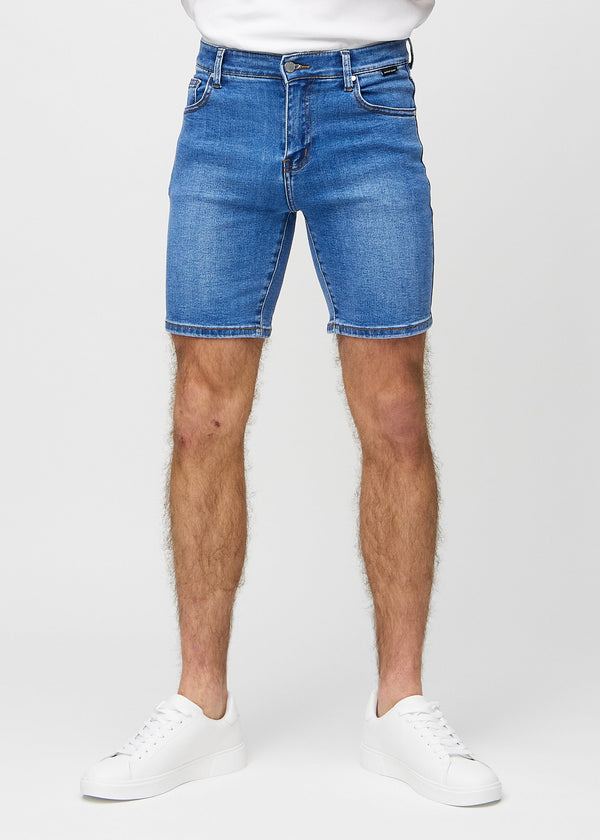 Blå denimshorts i middle-slim-passform, som följer låren och slutar strax ovanför knät, sedda framifrån.